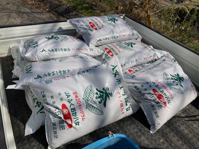お茶の肥料の大きな袋が軽トラックの荷台に積まれている様子。